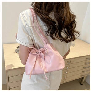 Vista laterale della borsa a secchiello rosa con fiocco a coulisse sulla tracolla elegante