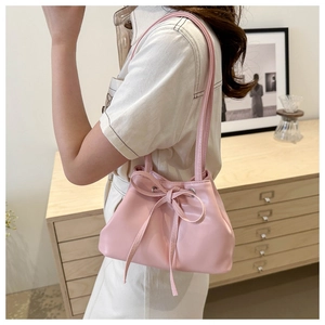 Vista dettagliata della borsa a secchiello in ecopelle rosa con coulisse a fiocco su modella