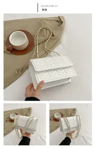 Detail of white quilted leather chain bag with elegant V-stitch pattern and metal strap