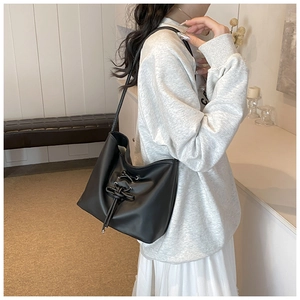 Detail of black soft PU bucket bag with cross-lace knot and elegant long shoulder strap