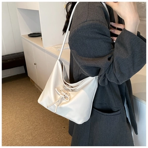 Detail of soft cream PU leather shoulder bag with decorative drawstring bow for women