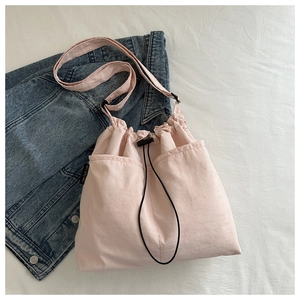 Detailed close-up of pink drawstring canvas bucket bag with adjustable shoulder strap