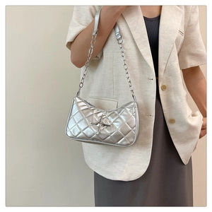 Silver quilted underarm bag featuring metallic star detail and chain strap worn on shoulder