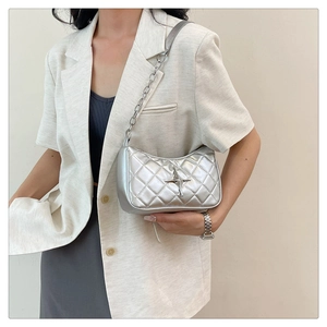 Detail of silver quilted shoulder bag with star charm and metallic chain strap