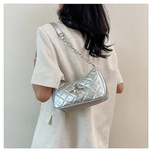 Detail of silver quilted underarm bag with metal star ornament and chain strap