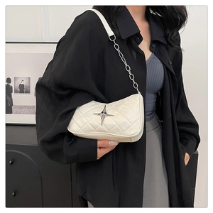 Close-up of white quilted handbag featuring a silver star metal buckle and chain strap