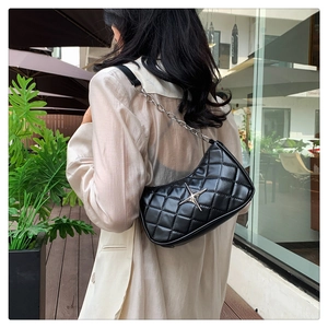 Classic black quilted leather shoulder bag with silver star buckle worn on a shoulder
