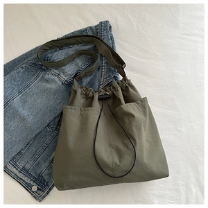 Detailed shot of an olive green canvas crossbody bag with drawstring closure and wide strap