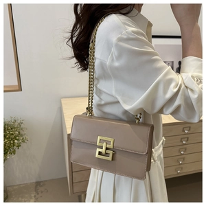 Detailed side view of a beige leather chain bag with a vintage gold geometric lock clasp