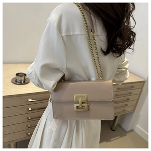 Side view of beige leather shoulder bag with gold chain strap worn by a model