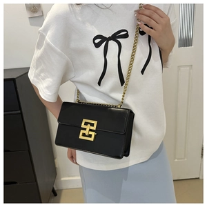 Detail of black leather crossbody bag with iconic gold link clasp and chain strap