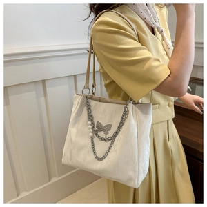 Détail du grand sac cabas crème avec chaîne argentée, papillon et accents de perles