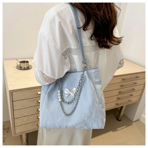 Détail du sac fourre-tout plissé bleu clair avec chaîne papillon et perles