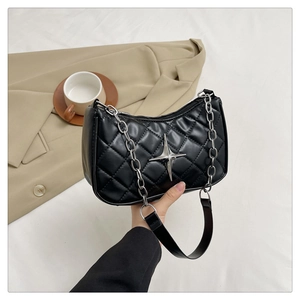 Detail of black quilted shoulder bag with star metal buckle and silver chain strap