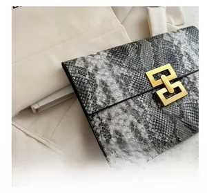 Détail de la pochette enveloppe grise effet peau de serpent avec fermoir doré géométrique