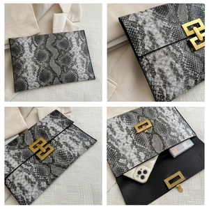 Gros plan de la pochette enveloppe en serpent avec boucle dorée et rangement intérieur