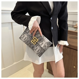 Détail d'une pochette enveloppe à motif serpent avec une boucle géométrique en métal doré