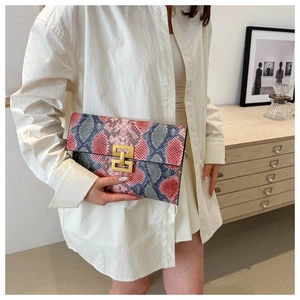 Détail de la pochette enveloppe motif serpent avec un fermoir en métal doré élégant