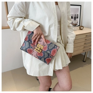 Gros plan sur la texture serpent multicolore et la boucle dorée de cette pochette
