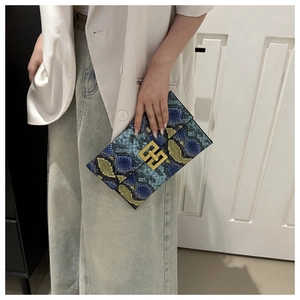 Vue détaillée d'une pochette enveloppe en cuir serpent avec boucle dorée imbriquée