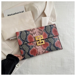 Détail de pochette en similicuir imprimé serpent avec boucle géométrique dorée élégante