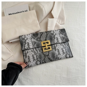 Détail d'une pochette enveloppe à motif serpent avec doubles boucles métalliques dorées