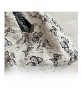 Close-up of white canvas tote bag featuring black butterfly print and boho fringe details