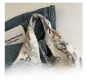 Detail of white tote bag featuring black butterfly print and unique frayed edge texture