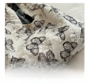 Detail of white tote bag with textured feather fabric and black butterfly prints