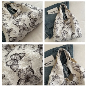 Detail of white chiffon tote bag featuring black butterfly prints and frayed fringe edges