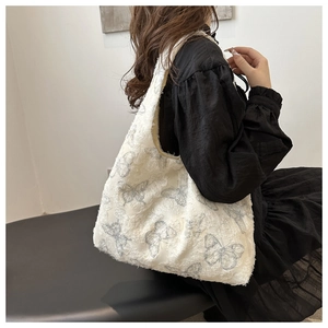 Detail of white plush tote bag with grey butterfly patterns and spacious interior