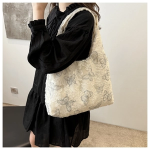 Detail view of large tote bag featuring grey butterfly embroidery on white textured fabric
