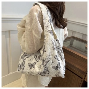 Detail view of white chiffon tote bag with black butterfly prints and fuzzy texture