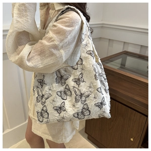 Off-white butterfly pattern chiffon tote bag with fringe texture shown on shoulder