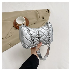 Detail of silver quilted shoulder bag featuring metallic star charm and chain strap