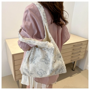 Detail of white plush shoulder bag featuring grey butterfly prints and spacious interior