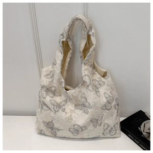 Detail of butterfly embroidery on cream chiffon tote bag with textured tassel fabric