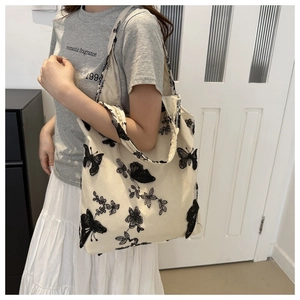 Detailed embroidery of black butterflies and floral lace on a beige canvas tote bag