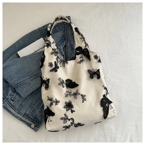 Close-up of black butterfly embroidery detail on white chiffon bucket shoulder bag