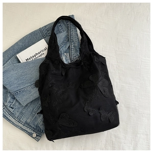 Close-up of intricate black butterfly embroidery on soft mesh lace tote bag texture