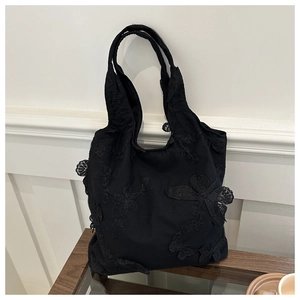 Detail of black canvas tote bag with 3D lace butterfly embroidery and long handles