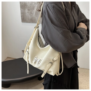 Détail du sac fourre-tout crème avec nœud métallique et lanières en cuir réglables en salle