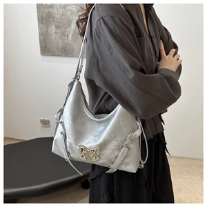 Sac à bandoulière argenté avec nœud métallique et texture plissée sur modèle