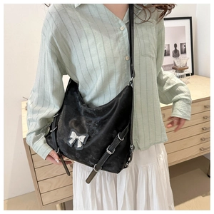 Détail macro du sac à bandoulière en cuir PU noir avec nœud argenté et boucles en métal