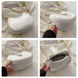Detail view of white half-moon bag featuring smooth leather and gold-tone buckles
