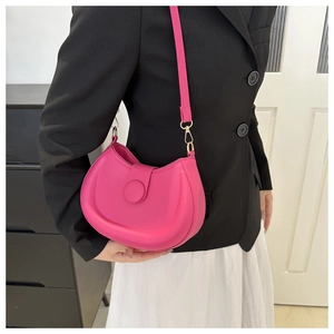 Detail of bright pink crescent crossbody bag with smooth texture and round buckle