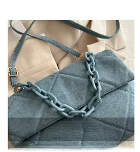 Detail view of light blue quilted denim texture with chunky plastic chain handle