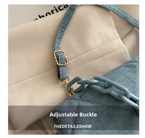 Detail of adjustable gold buckle and blue plastic chain on a denim shoulder bag