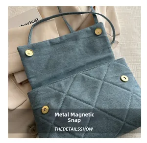 Detail of the golden magnetic snap closures on a quilted denim blue envelope bag