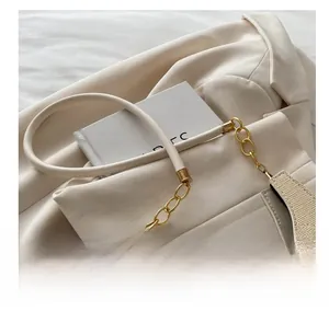 Detail of soft cream leather cylindrical shoulder strap with elegant gold metal chain links